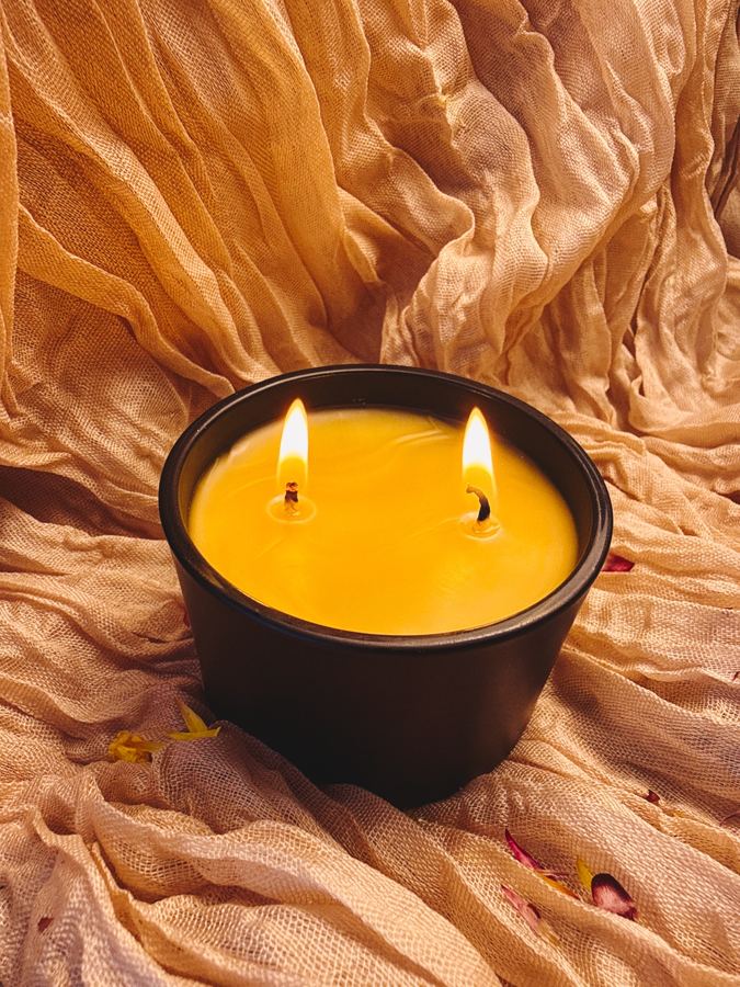 Two-wick beeswax candle in a matte black jar, lit