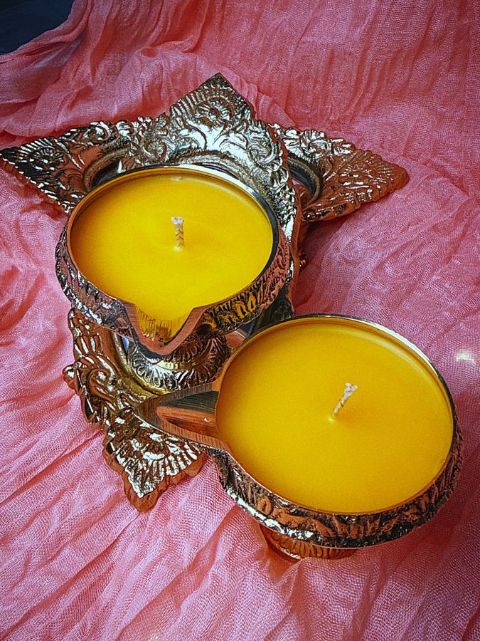 Two brass pedestal diyas poured with yellow beeswax