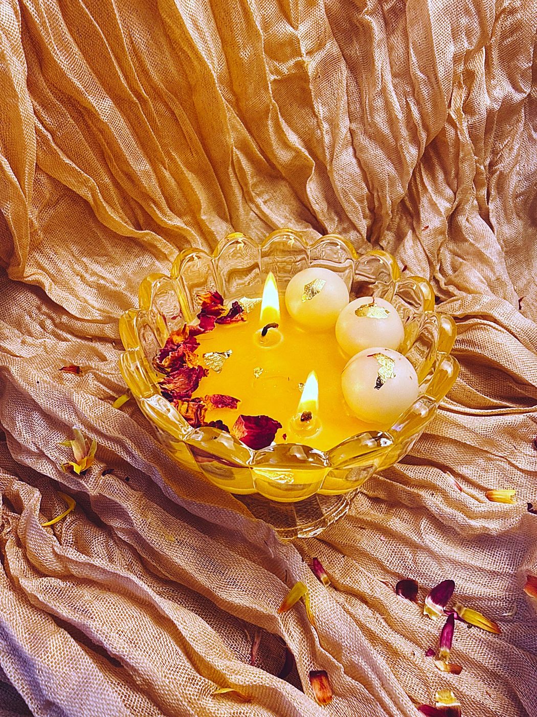 Ras Malai beeswax candle lit in a glass lotus bowl with beeswax rasgulla, rose petals and gold flakes